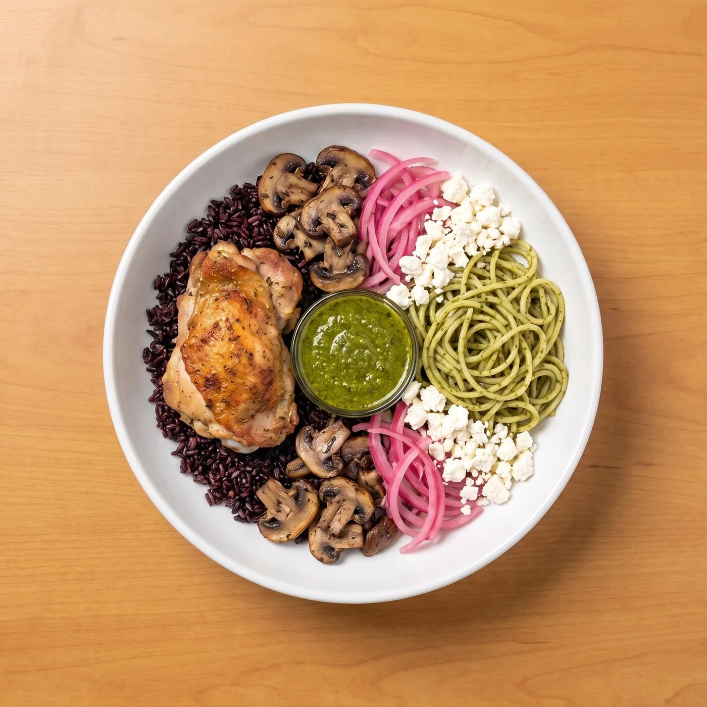 Herb Pesto Chicken Bol: Rotisserie chicken thigh over 100% black rice and pesto noodles, layered with thyme roasted mushrooms, pickled red onions, and creamy feta, finished with herb pesto.
